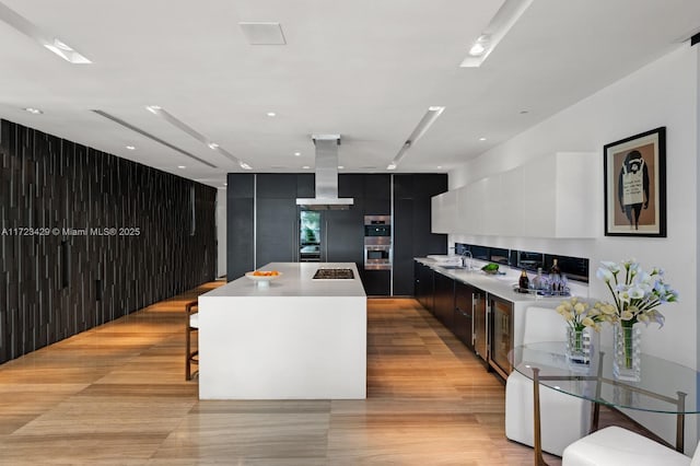 kitchen featuring a large island, light tile patterned floors, island exhaust hood, a kitchen bar, and stainless steel double oven