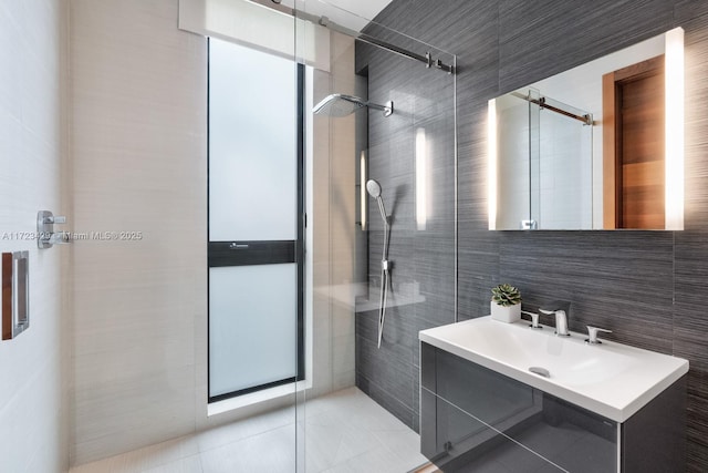 bathroom with tile walls, vanity, tile patterned flooring, and tiled shower