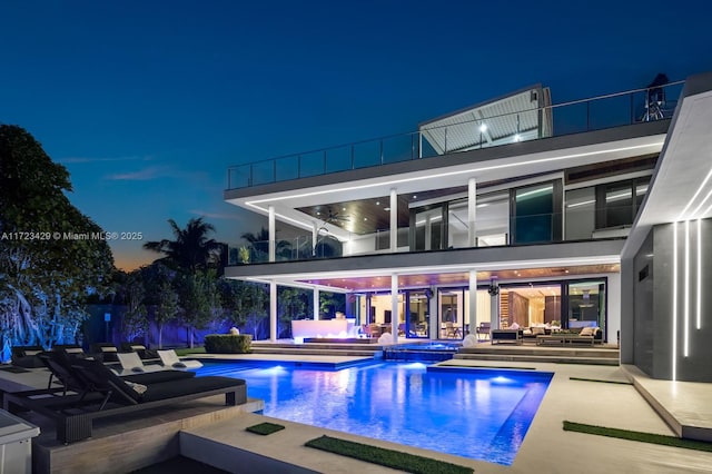 pool at night featuring a patio and an in ground hot tub