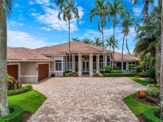 mediterranean / spanish-style home with a garage and french doors