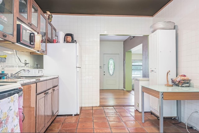 kitchen featuring decorative backsplash, separate washer and dryer, tile walls, range with electric stovetop, and light tile patterned flooring