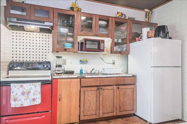 kitchen featuring tile countertops, decorative backsplash, white appliances, and sink