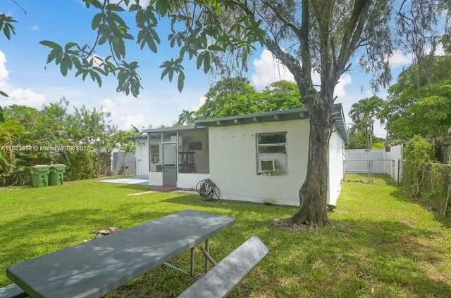 back of property with a lawn and a sunroom