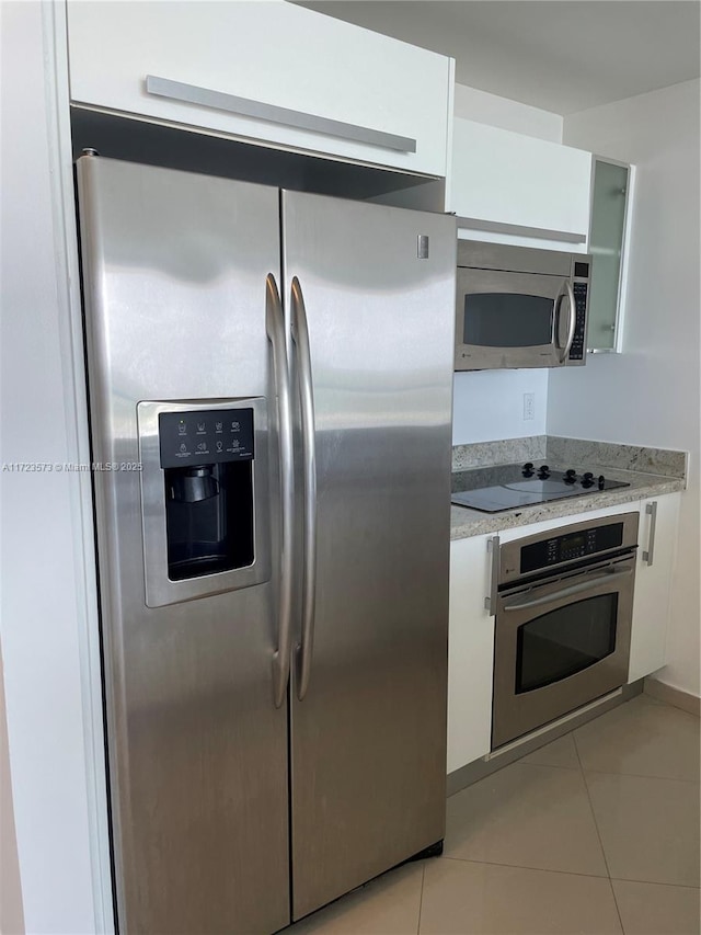 kitchen featuring white cabinets, stainless steel appliances, and light tile patterned floors