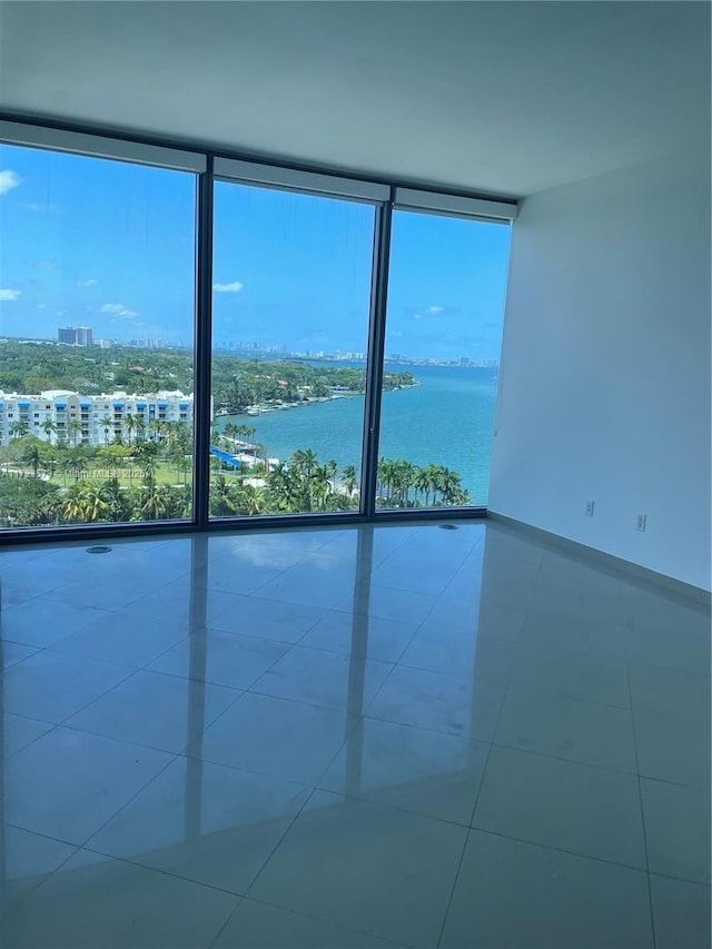 unfurnished room featuring tile patterned floors, floor to ceiling windows, and a water view