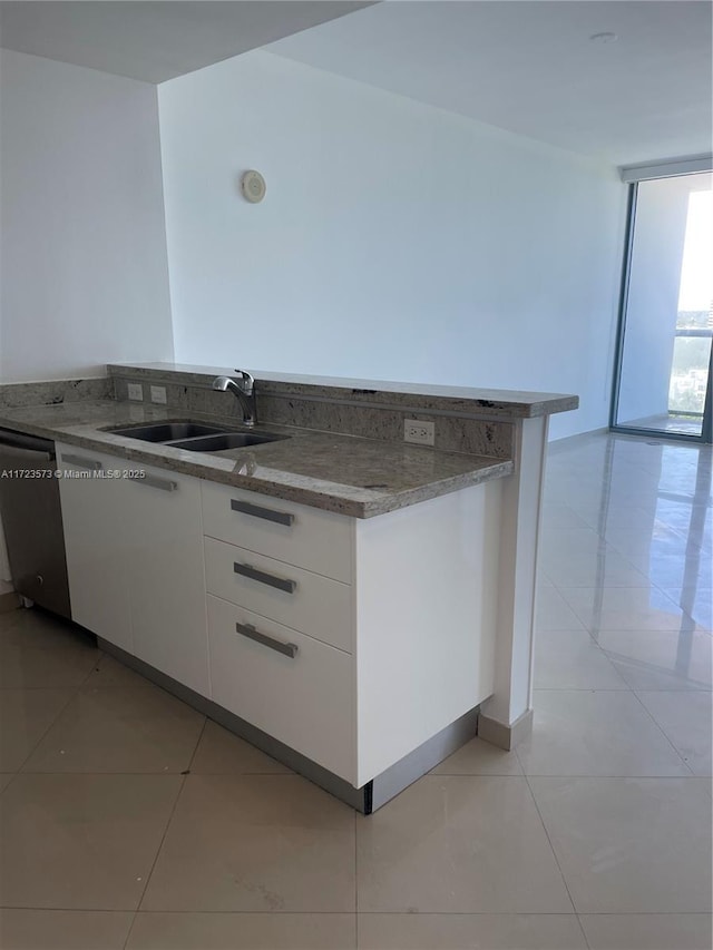 kitchen featuring dishwasher, floor to ceiling windows, white cabinets, sink, and light tile patterned flooring