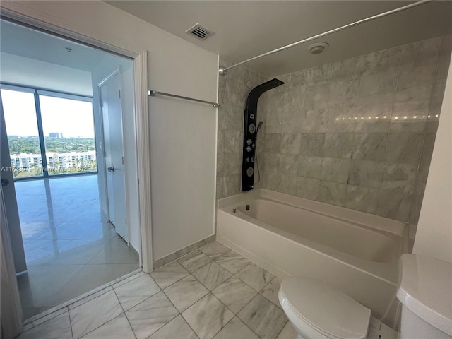 bathroom with toilet and tiled shower / bath