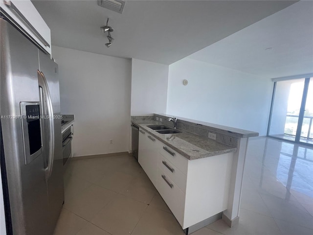 kitchen featuring track lighting, sink, appliances with stainless steel finishes, white cabinetry, and kitchen peninsula