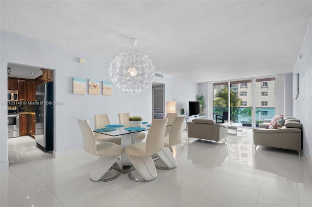 dining space with a notable chandelier, expansive windows, light tile patterned floors, and a textured ceiling