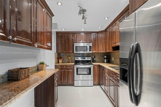 kitchen featuring backsplash, light stone countertops, light tile patterned floors, and appliances with stainless steel finishes