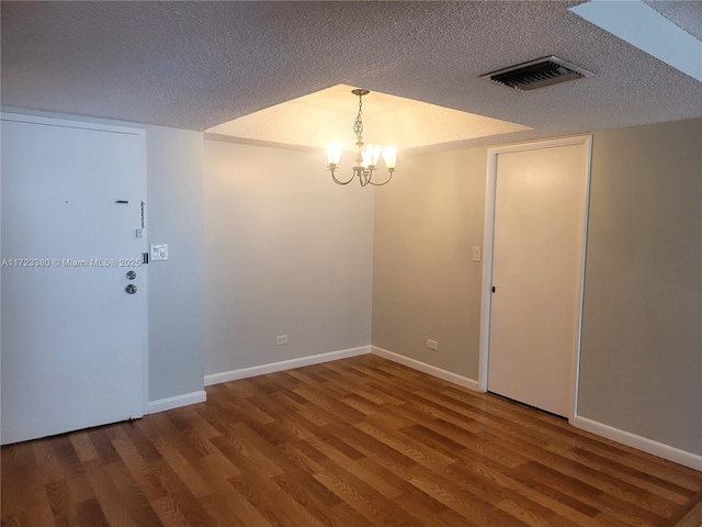 unfurnished room featuring hardwood / wood-style floors, a chandelier, and a textured ceiling