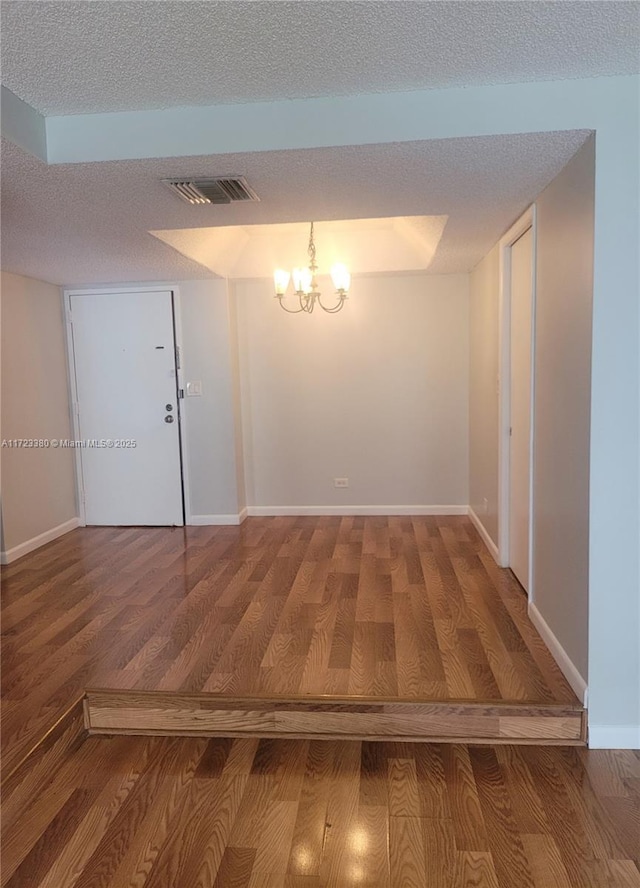 interior space featuring hardwood / wood-style floors, a textured ceiling, and an inviting chandelier