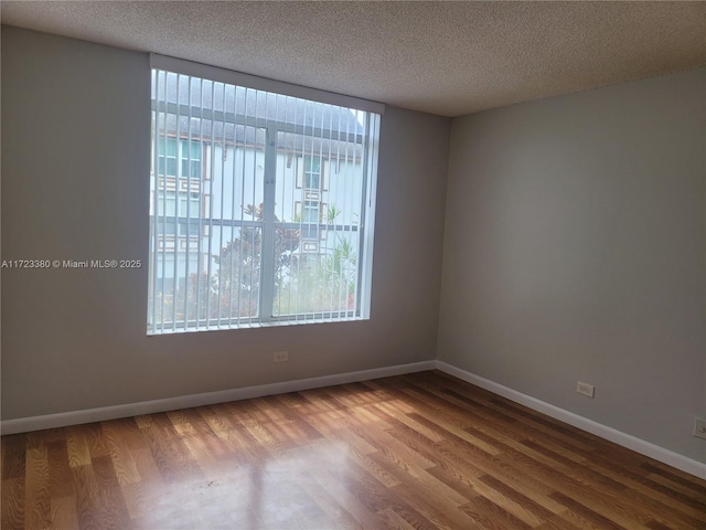 empty room featuring wood-type flooring and a textured ceiling