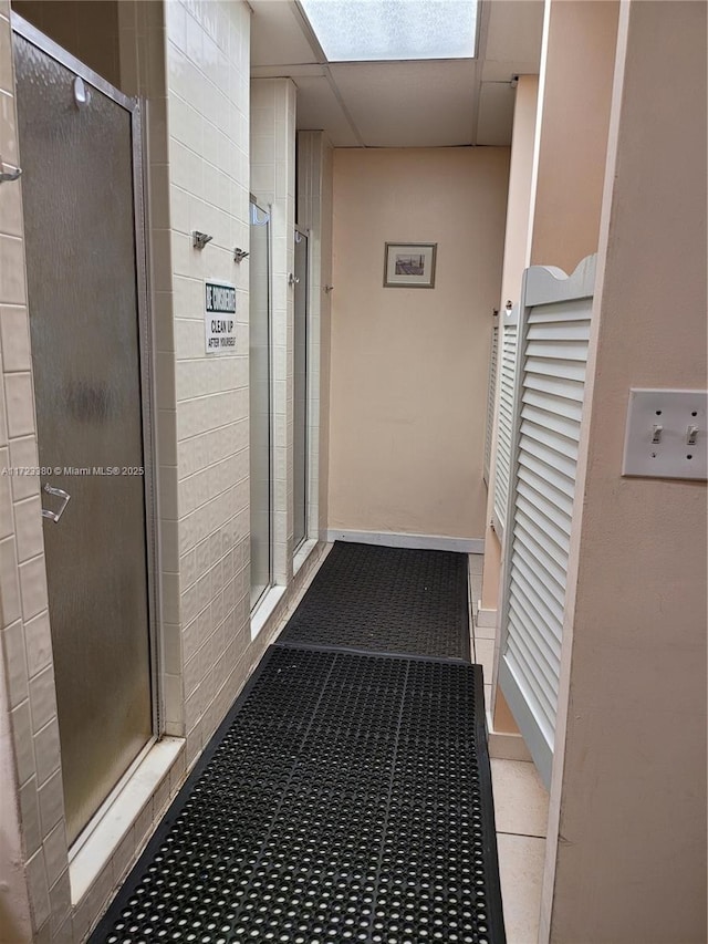 corridor with a paneled ceiling and light tile patterned flooring