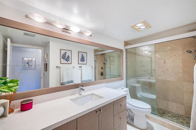 bathroom featuring vanity, a shower with shower door, and toilet