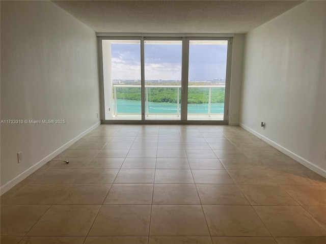 unfurnished room featuring light tile patterned floors, a textured ceiling, and a wall of windows