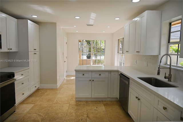 kitchen featuring sink, stainless steel appliances, kitchen peninsula, decorative backsplash, and white cabinets