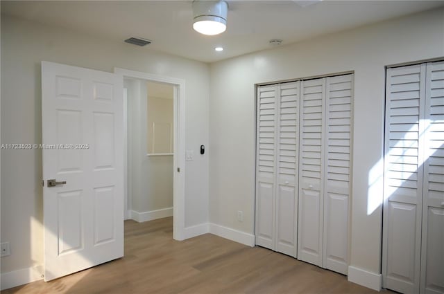 bedroom featuring light hardwood / wood-style flooring and two closets