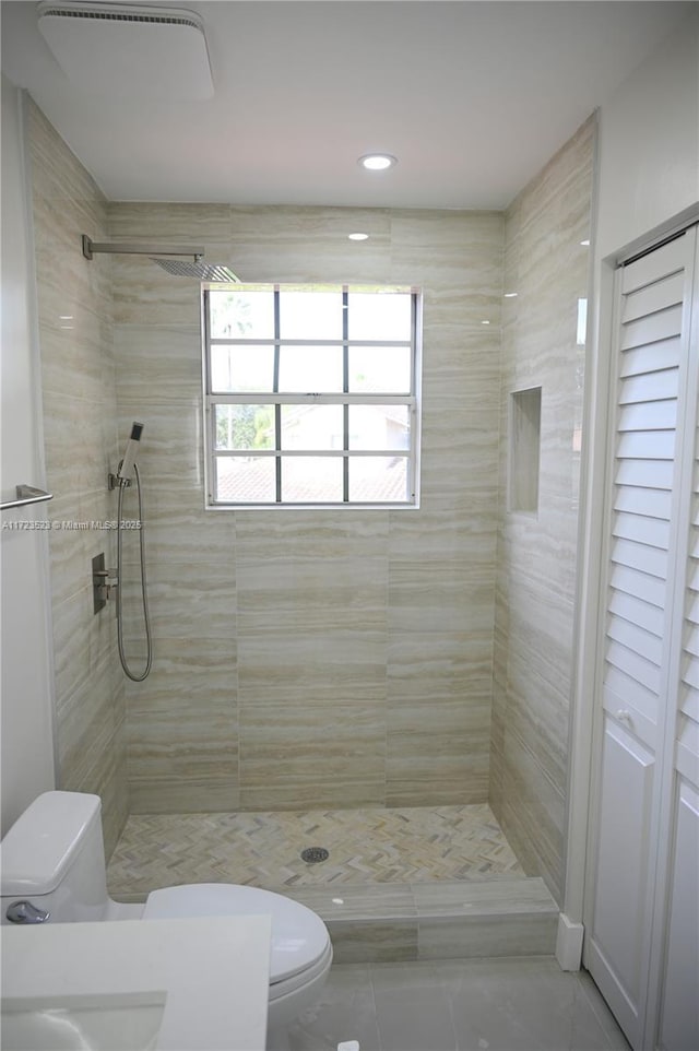 bathroom with tile patterned flooring, a tile shower, and toilet