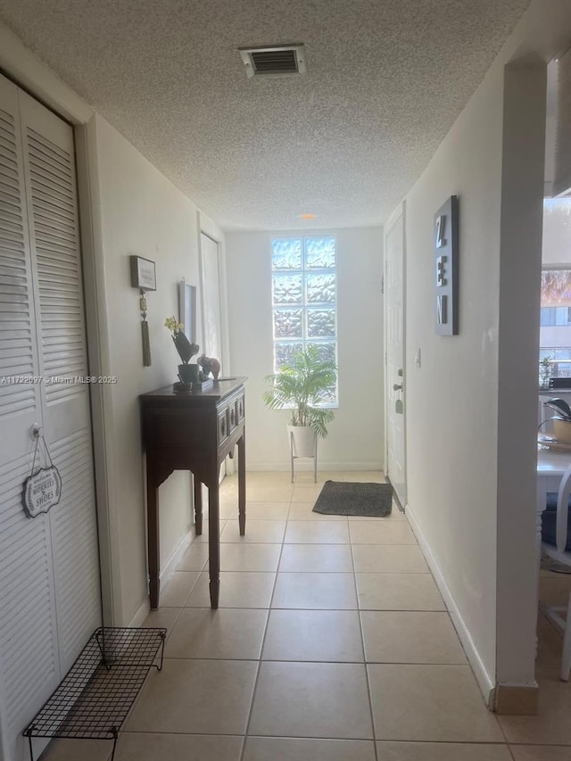 hallway with light tile patterned flooring and a textured ceiling