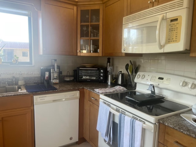 kitchen with decorative backsplash, white appliances, and dark stone countertops