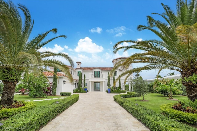 mediterranean / spanish-style home with a balcony and a front lawn