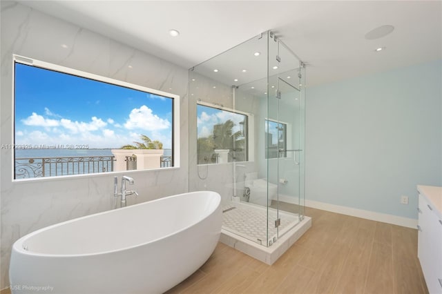 bathroom with vanity, hardwood / wood-style floors, a water view, and shower with separate bathtub