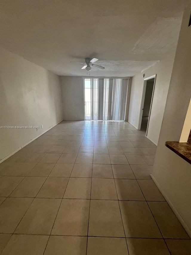 tiled empty room featuring ceiling fan