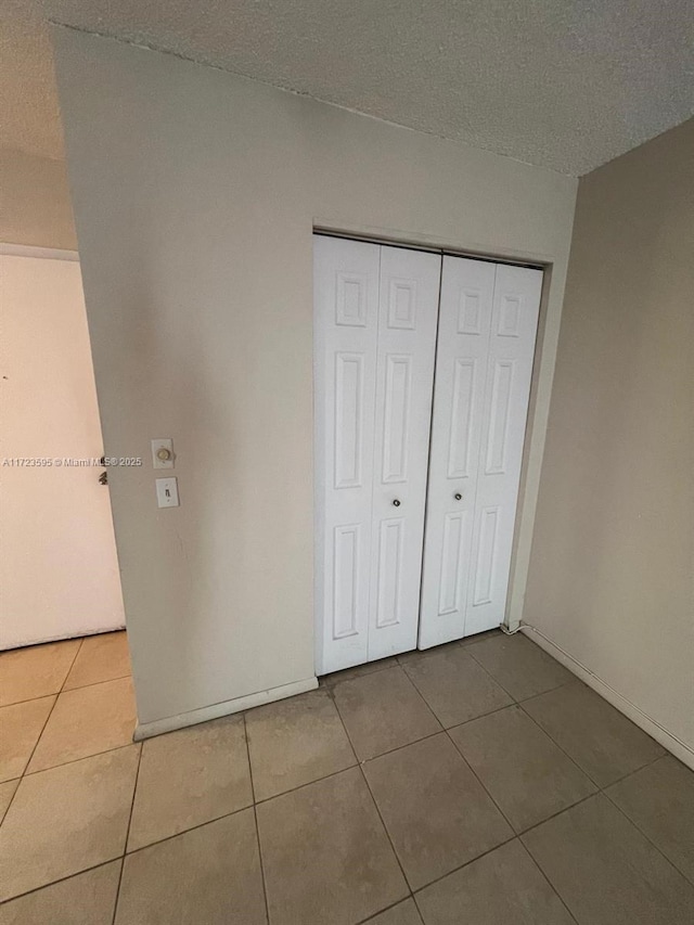 unfurnished bedroom with tile patterned flooring, a textured ceiling, and a closet