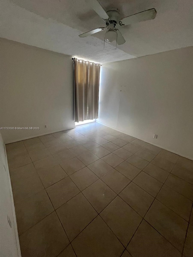 tiled spare room with ceiling fan