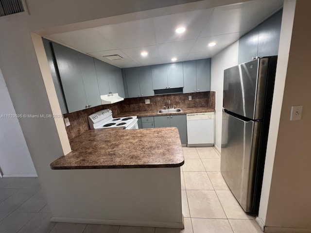 kitchen with kitchen peninsula, decorative backsplash, white appliances, sink, and light tile patterned floors