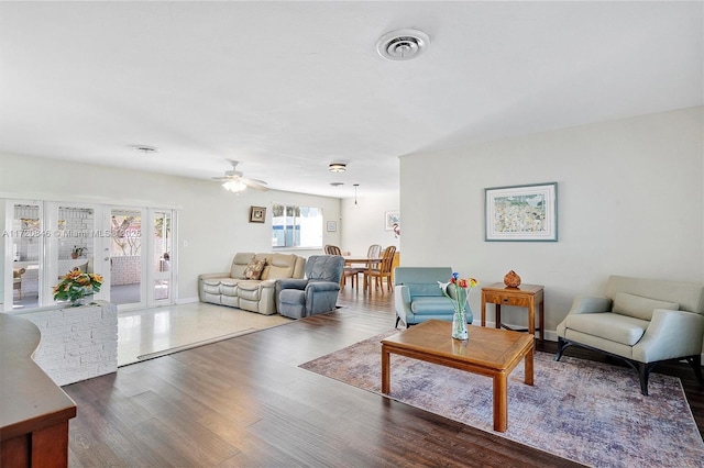 living room with ceiling fan and dark wood-type flooring