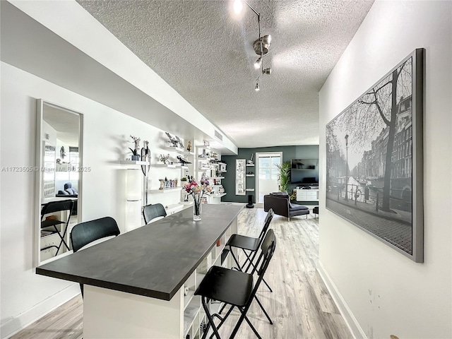 dining area with light hardwood / wood-style flooring, rail lighting, and a textured ceiling