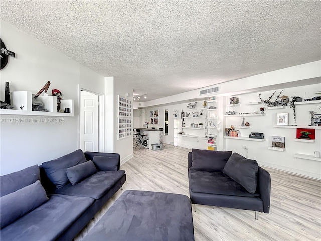 living room with a textured ceiling and light hardwood / wood-style flooring