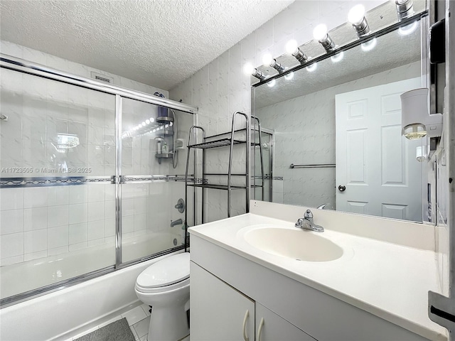 full bathroom with tile patterned floors, a textured ceiling, vanity, shower / bath combination with glass door, and toilet