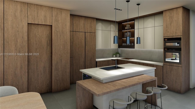 kitchen featuring pendant lighting, a kitchen breakfast bar, sink, light tile patterned floors, and a kitchen island