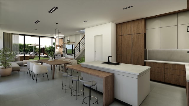 kitchen featuring floor to ceiling windows, white cabinetry, sink, pendant lighting, and a kitchen island with sink