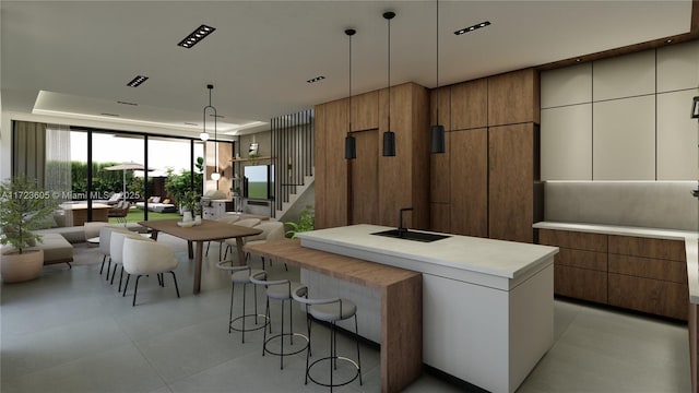 kitchen featuring white cabinetry, a center island with sink, hanging light fixtures, and sink