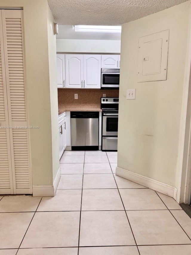 kitchen with dishwasher, stove, white cabinets, and light tile patterned floors