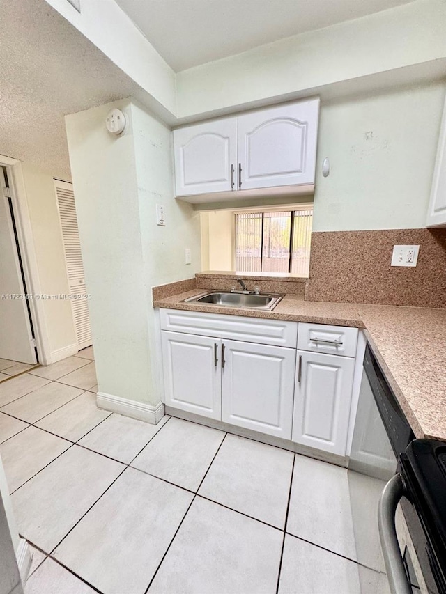 kitchen featuring white cabinetry, sink, tasteful backsplash, light tile patterned floors, and range