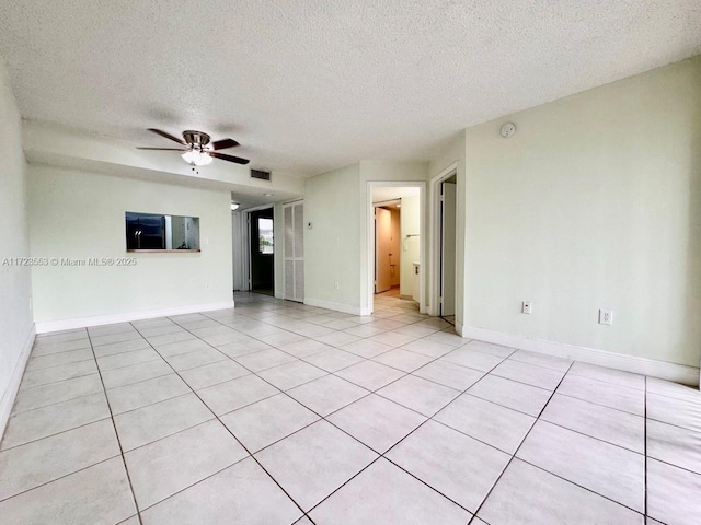 tiled empty room with ceiling fan and a textured ceiling