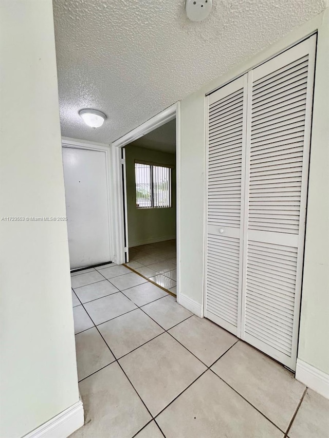 corridor with light tile patterned floors and a textured ceiling