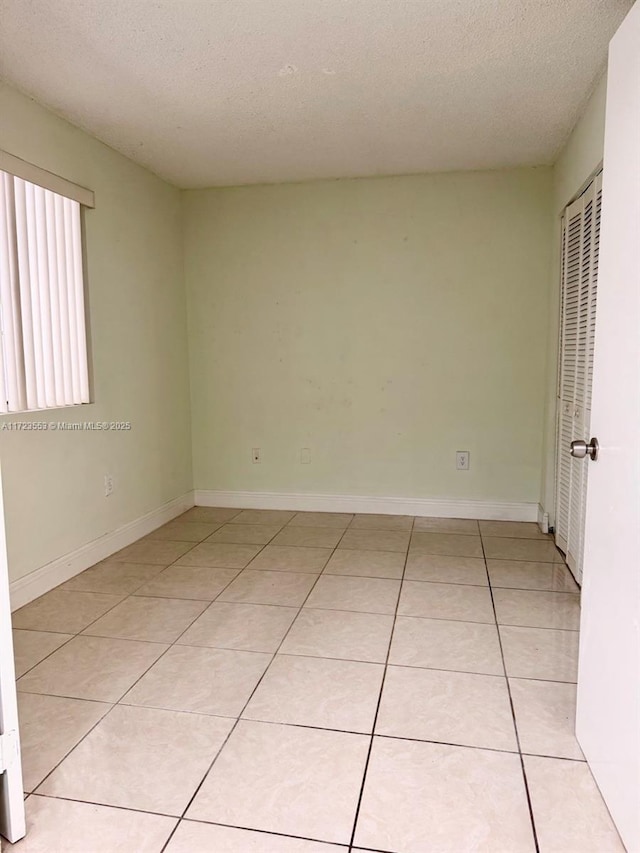 spare room featuring light tile patterned floors and a textured ceiling