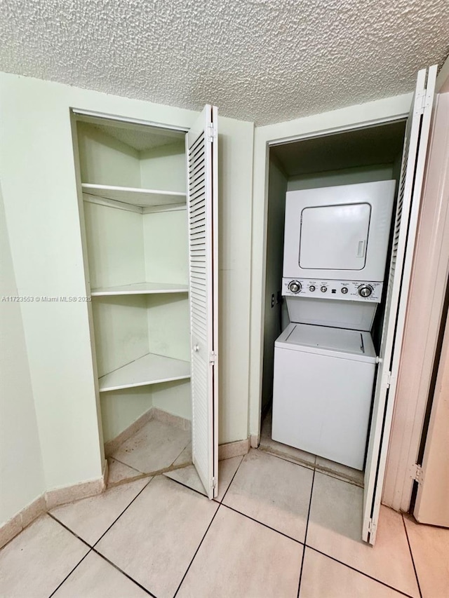 laundry area with light tile patterned flooring and stacked washer and clothes dryer