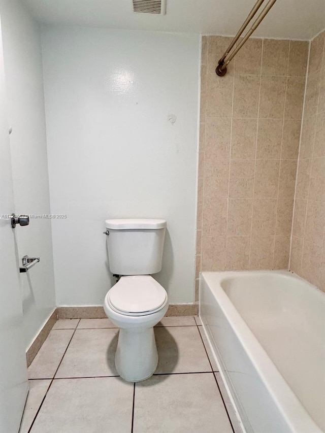 bathroom featuring toilet, tile patterned floors, and tiled shower / bath