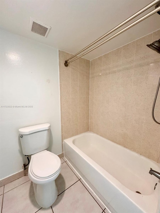 bathroom featuring tile patterned flooring, tiled shower / bath combo, and toilet