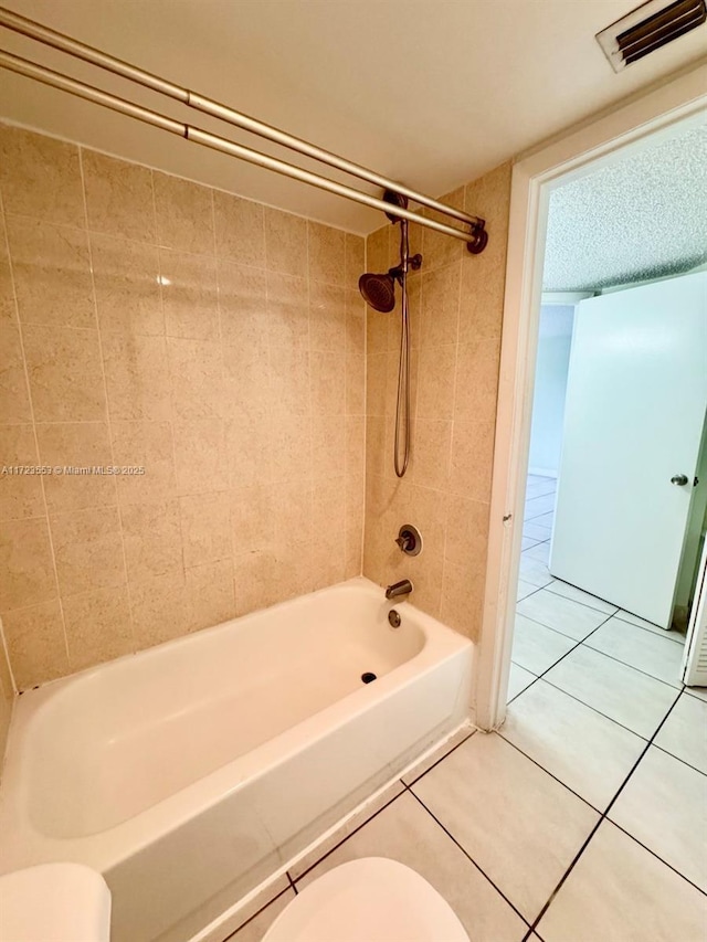 bathroom featuring tile patterned flooring, tiled shower / bath combo, and toilet