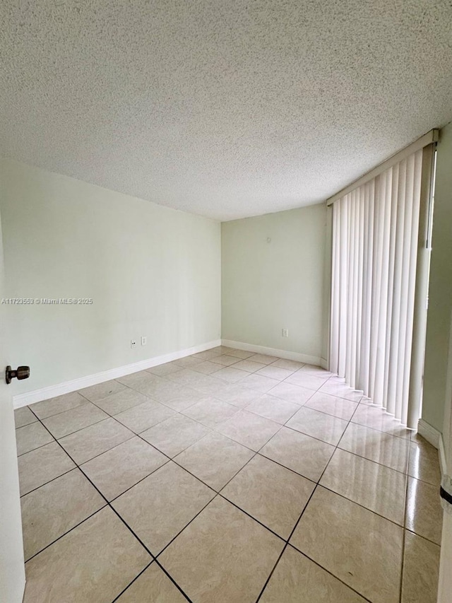 tiled empty room featuring a textured ceiling