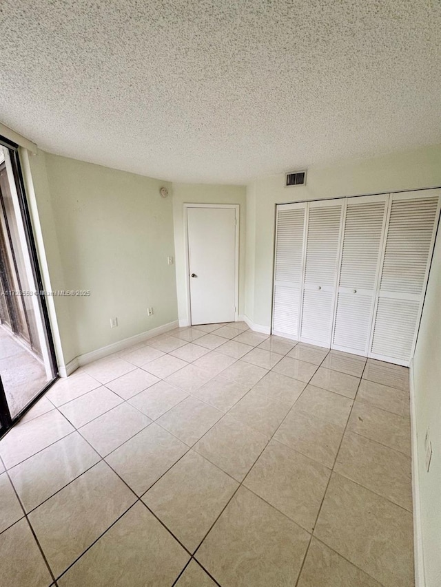 unfurnished bedroom with light tile patterned floors, a textured ceiling, and a closet