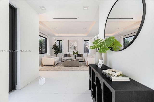 corridor featuring a raised ceiling and light tile patterned flooring